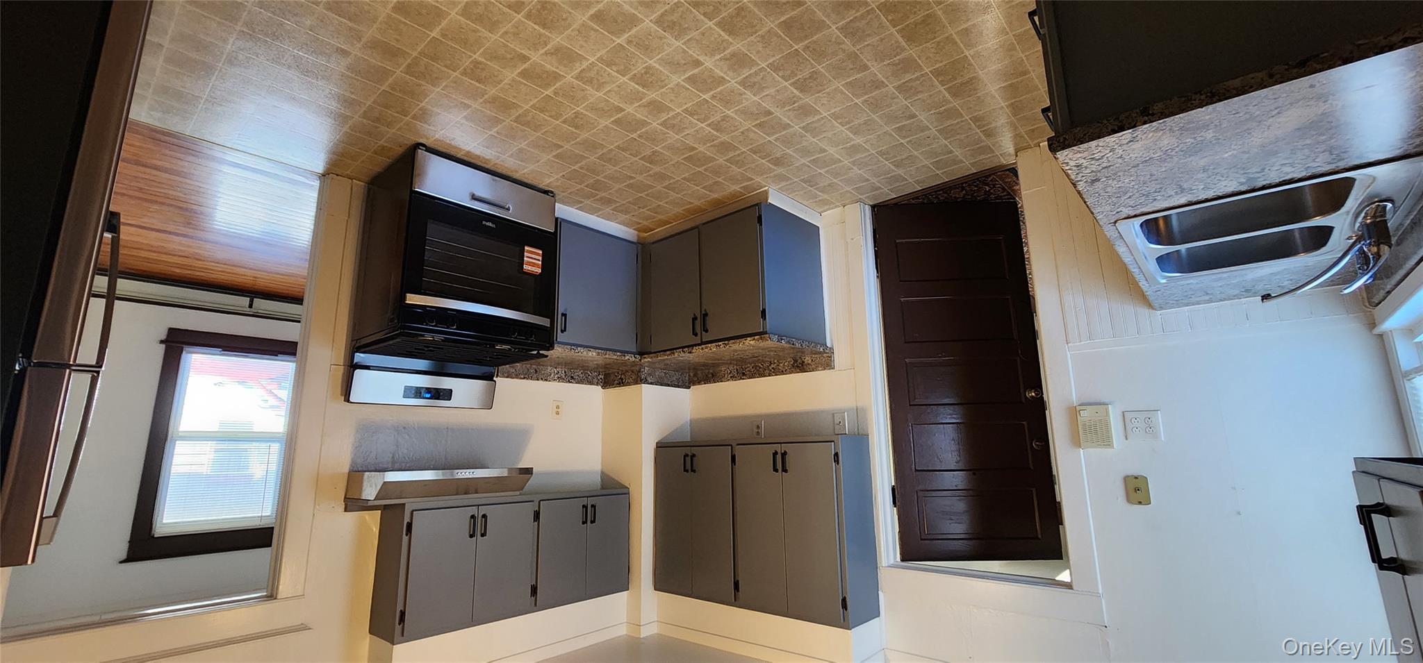 20 Delaware Street, Unit 1 Port Jervis, NY 12771 - Photo 3 of 12 Kitchen with gray cabinets, dark countertops, stove, fridge, and wainscoting