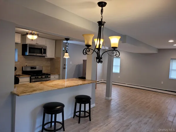 a kitchen with stainless steel appliances a dining table chairs stove and microwave