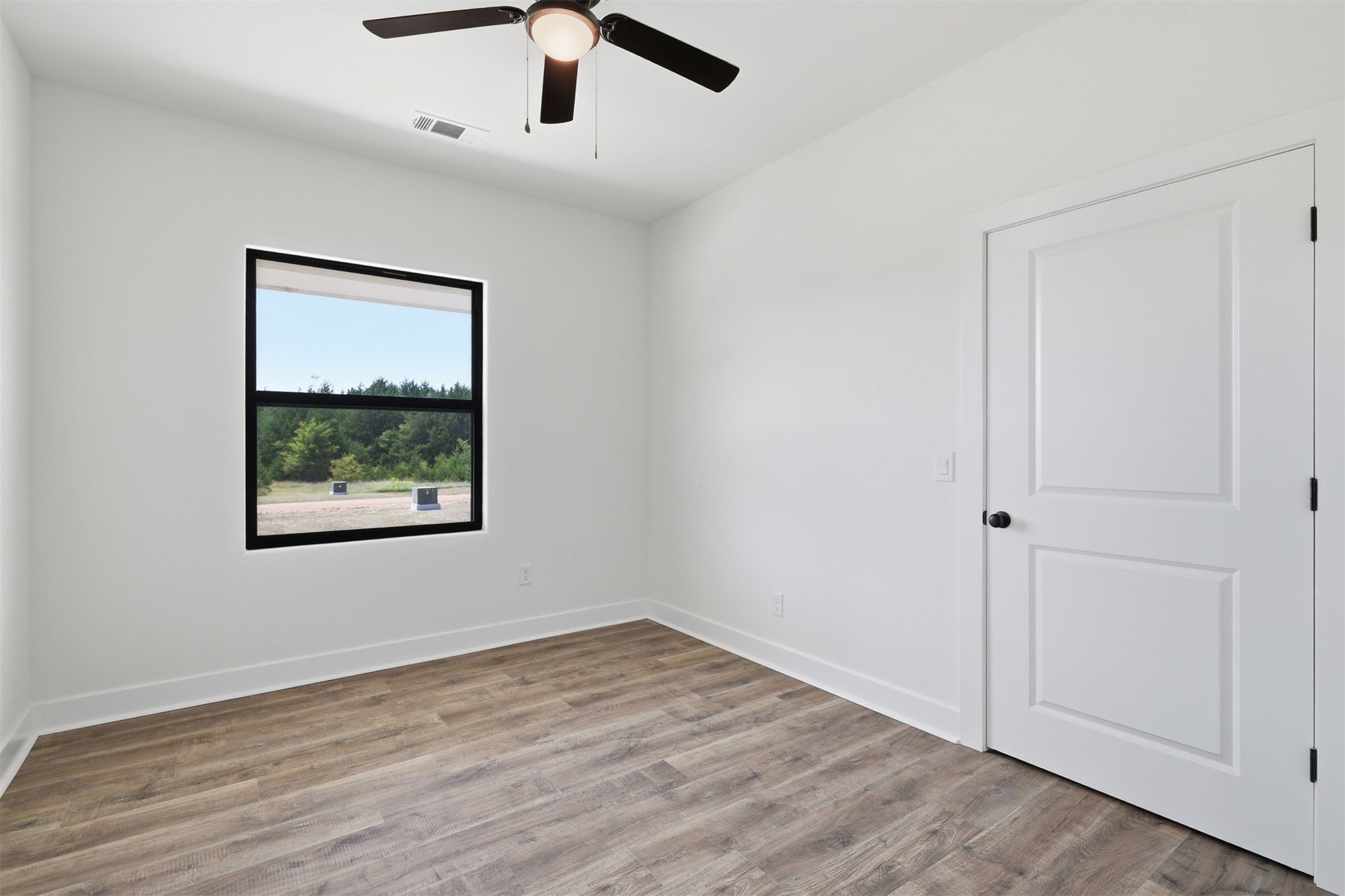63 Deerfield Road Colbert, OK 74733 - Photo 21 of 33 Bedroom featuring wood-finish flooring, a contemporary ceiling fan with integrated lighting, a two-panel interior door, and a black-framed window