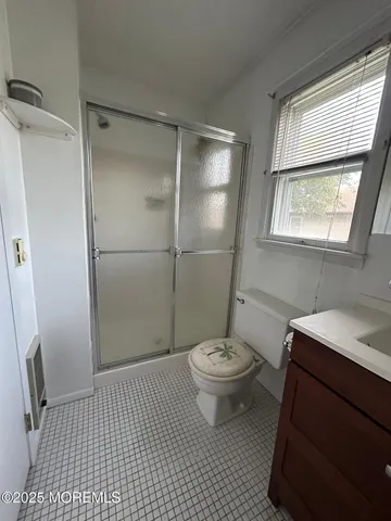 a bathroom with a sink a toilet a window and shower
