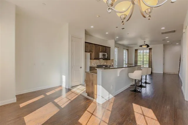 a living room with stainless steel appliances furniture a rug and a view of kitchen
