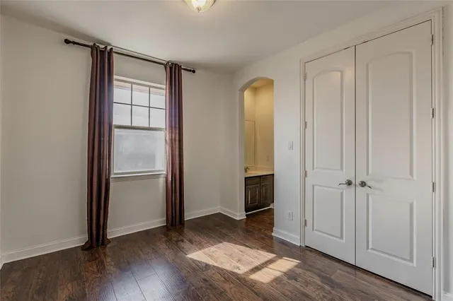 an empty room with wooden floor closet and windows