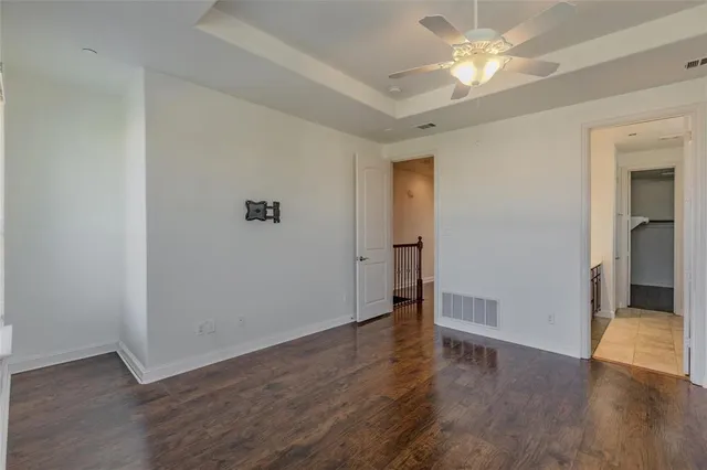 an empty room with wooden floor and ceiling fan