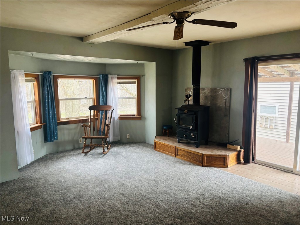 685 Furnace Road Conneaut, OH 44030 - Photo 11 of 22 Living room featuring beamed ceiling, carpet flooring, and a wood stove