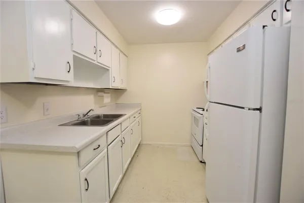 a kitchen with a sink a refrigerator and cabinets