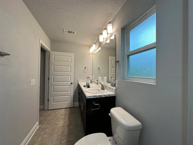 a bathroom with a toilet a sink a mirror a vanity and window