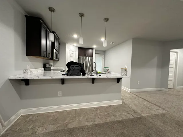 a kitchen with kitchen island a sink stainless steel appliances and a counter top space