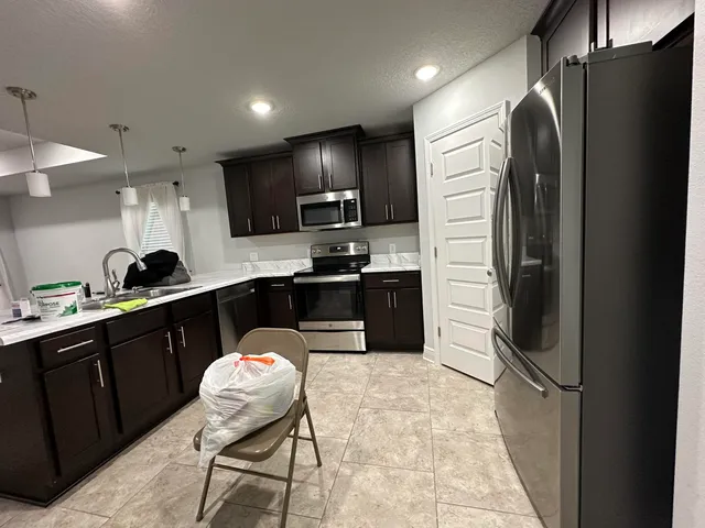 a kitchen with stainless steel appliances granite countertop a refrigerator a sink a stove and microwave