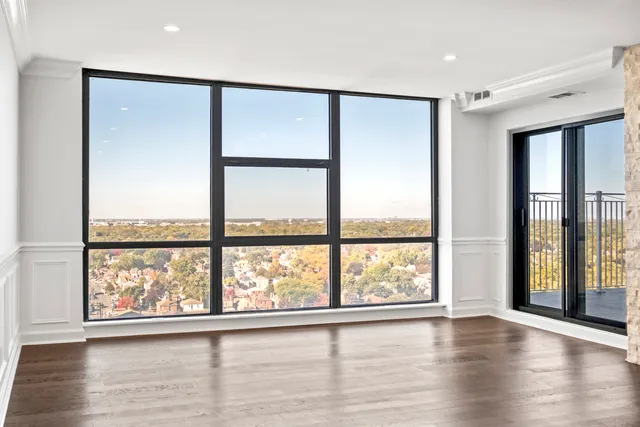 an empty room with wooden floor and windows with curtains