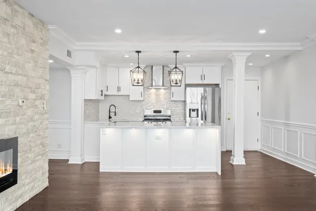 a large white kitchen with lots of counter space wooden floor and stainless steel appliances