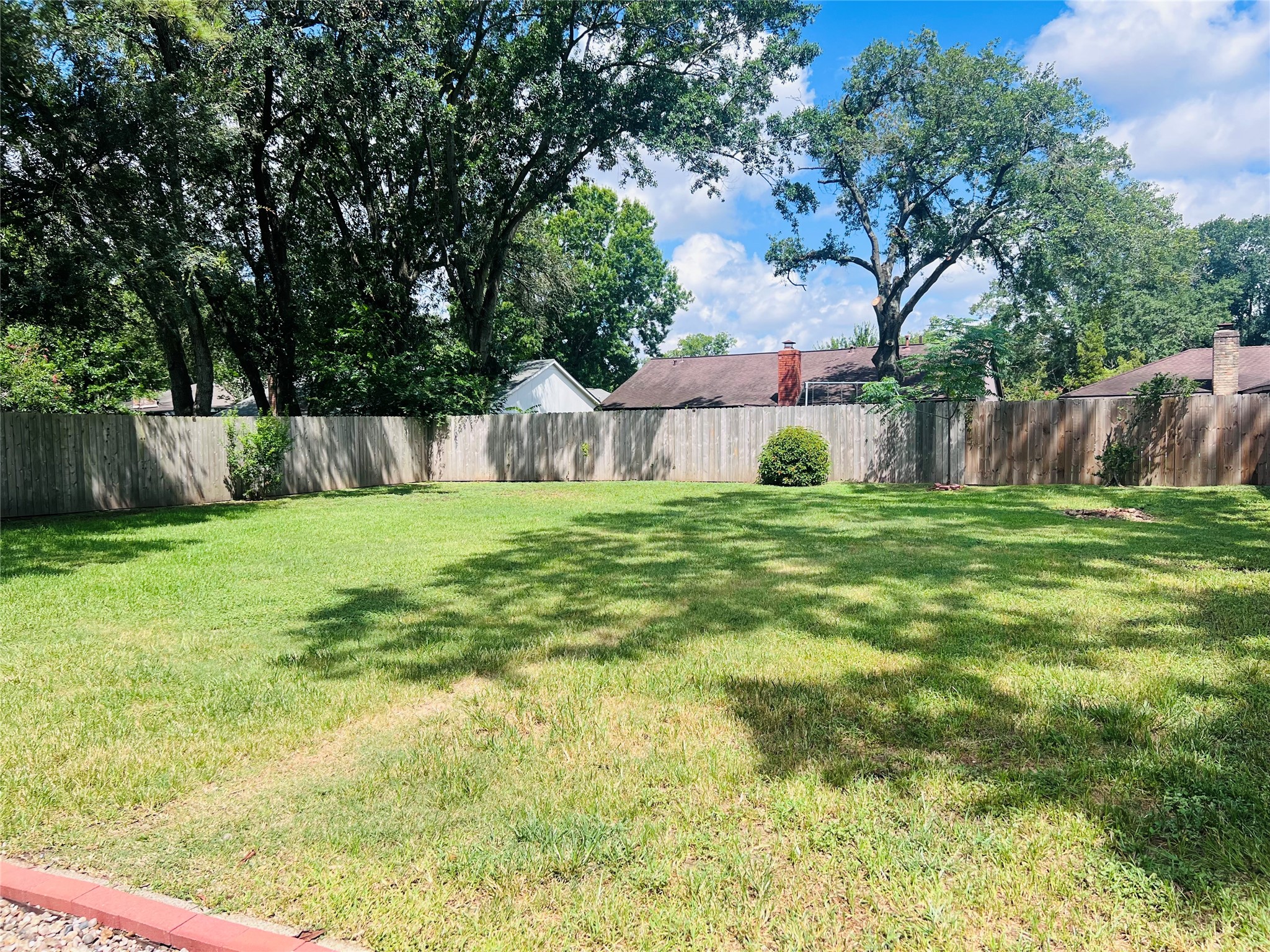902 Hidden Canyon Road Katy, TX 77450 - Photo 18 of 20 A spacious, well-maintained backyard with lush green grass and mature trees. It features a wooden privacy fence, offering a serene and private outdoor space ideal for relaxation or entertaining.