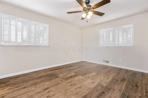 a view of an empty room with window and a chandelier fan