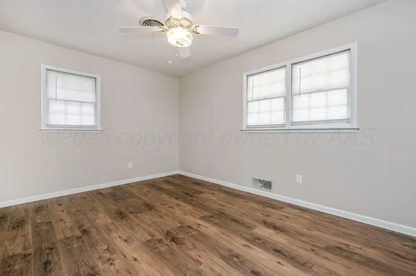 a view of empty room with wooden floor and fan