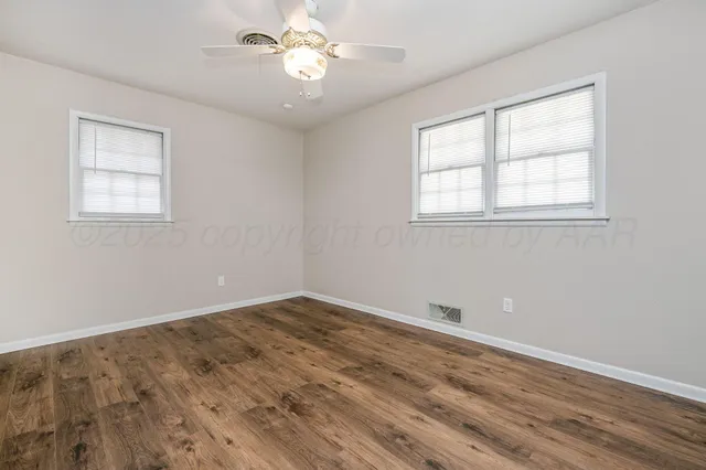 a view of empty room with wooden floor and fan