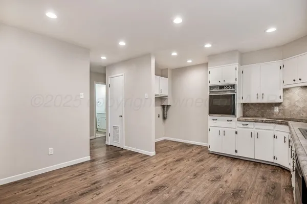 a large kitchen with cabinets and wooden floor