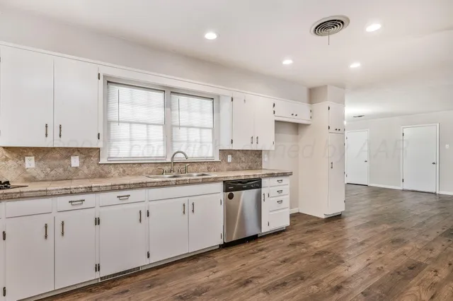 a large kitchen with granite countertop a white stove top oven and white cabinets