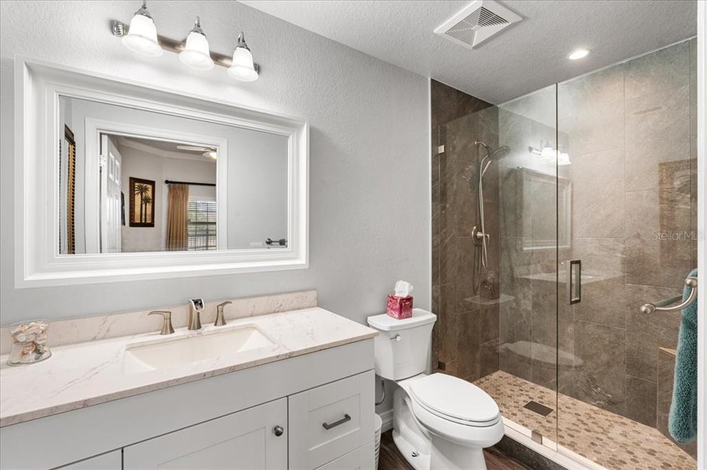 7658 Whisper Way, Unit 402 Reunion, FL 34747 - Photo 22 of 31 a bathroom with a granite countertop sink toilet a mirror and shower
