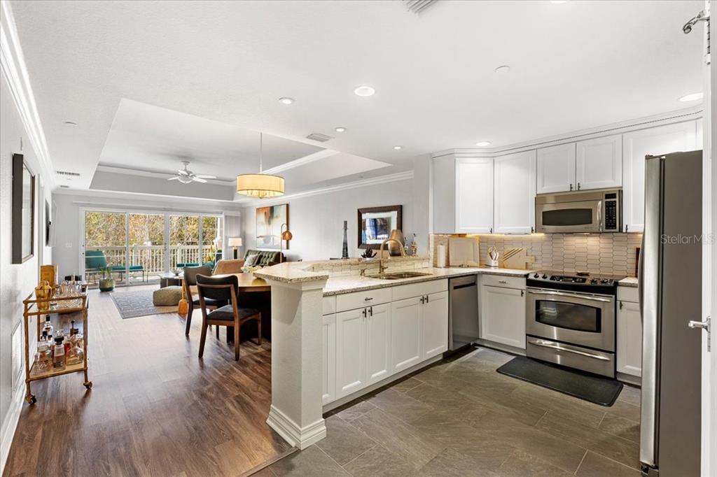 7658 Whisper Way, Unit 402 Reunion, FL 34747 - Photo 3 of 31 a kitchen with stainless steel appliances granite countertop a stove top oven a sink dishwasher a dining table and chairs with wooden floor