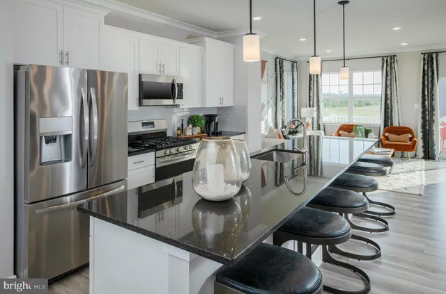 a kitchen with stainless steel appliances granite countertop a refrigerator a stove a sink a dining table and chairs