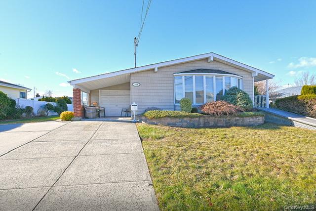 View of front of home with concrete driveway, a front lawn, and an attached garage