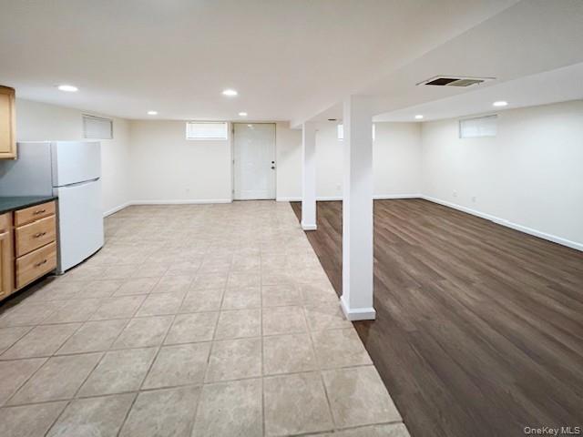 122 Miller Road Hicksville, NY 11801 - Photo 19 of 27 Finished basement with freestanding refrigerator, light tile patterned flooring, and recessed lighting
