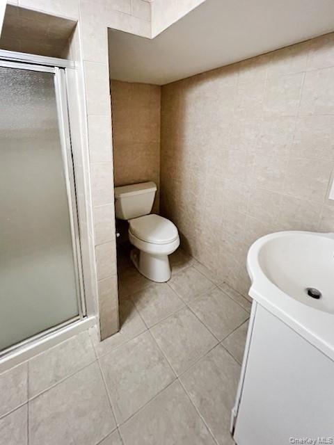 122 Miller Road Hicksville, NY 11801 - Photo 22 of 27 Full bath featuring vanity, a shower stall, tile walls, and light tile patterned floors