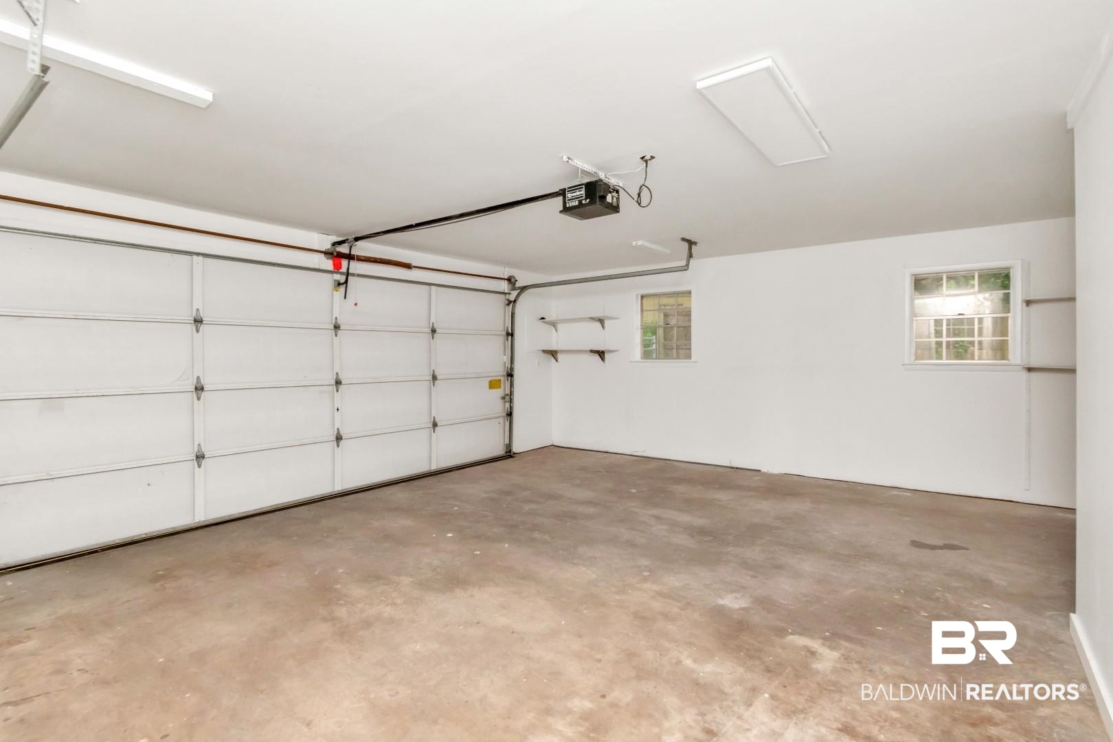 5217 Perin Road Mobile, AL 36693 - Photo 6 of 45 Spacious garage featuring a white overhead door, concrete flooring, and built-in shelving