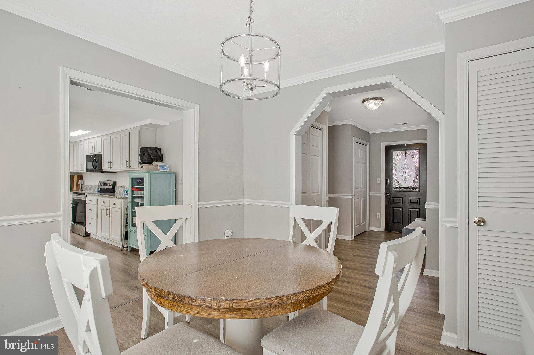 114 River Road Edgewater, MD 21037 - Photo 16 of 30 a dining room with wooden floor a chandelier a wooden table and chairs