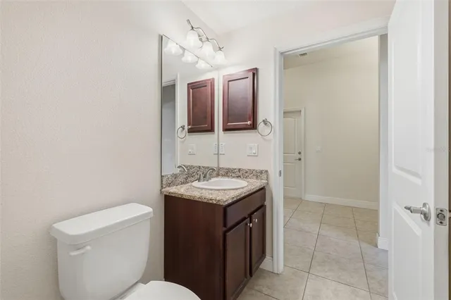 a bathroom with a granite countertop sink a mirror and a toilet