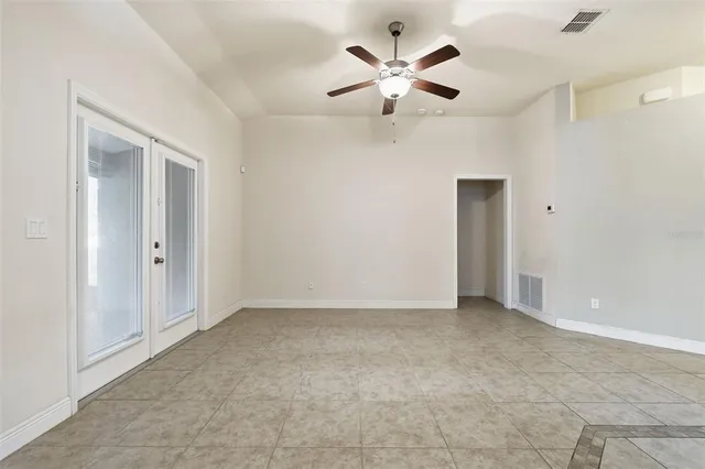 a view of an empty room with a chandelier fan