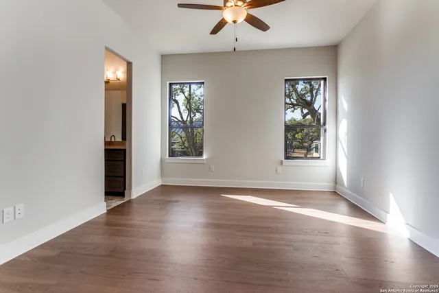 a view of an empty room with window and wooden floor