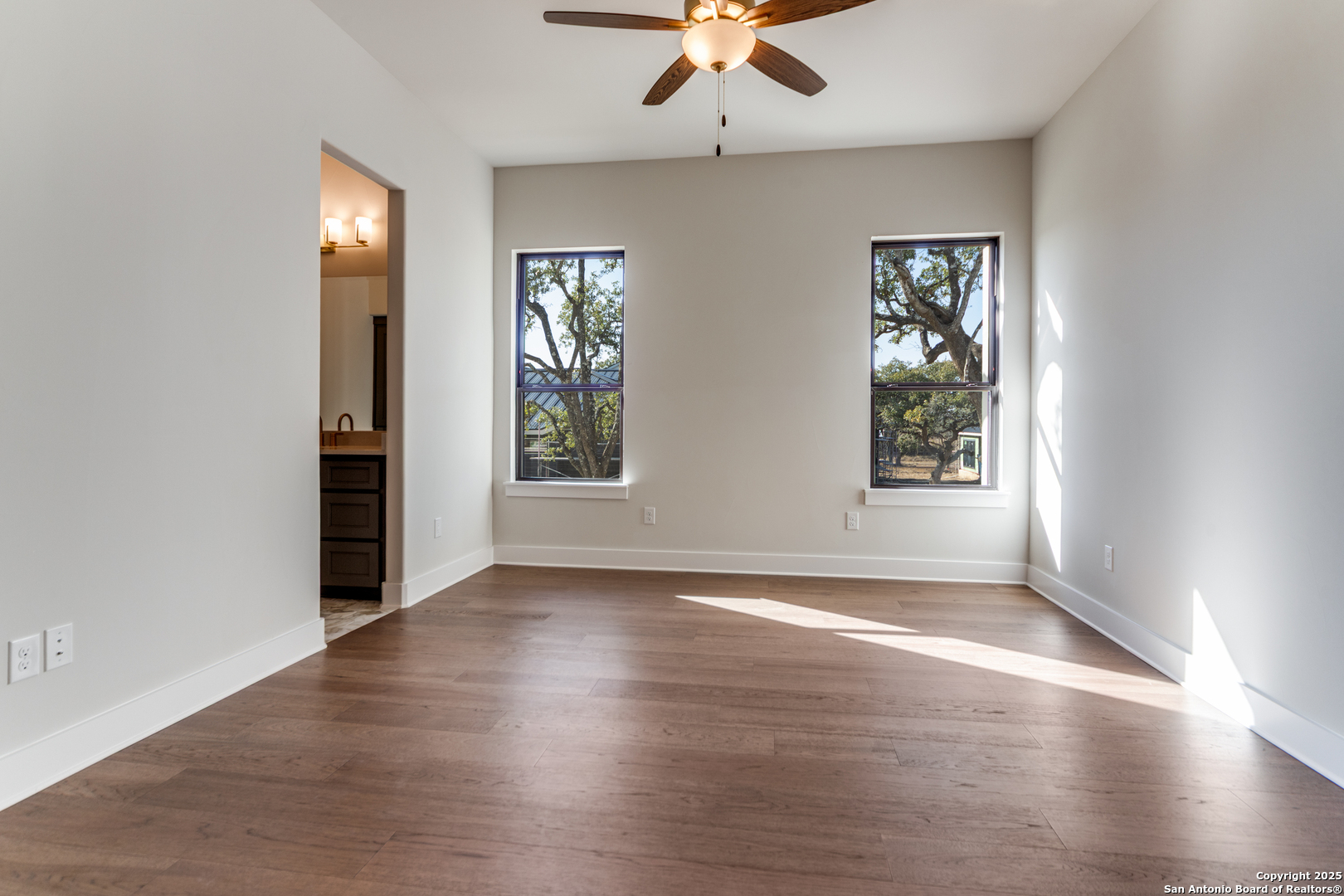 193 Ranch Heights Boerne, TX 78015 - Photo 20 of 29 an empty room with wooden floor chandelier fan and windows