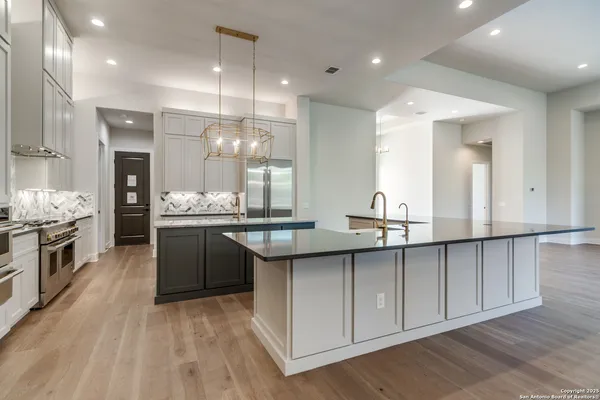 a kitchen with stainless steel appliances granite countertop a sink a stove and a wooden floors
