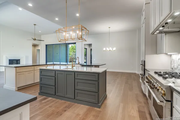a kitchen with stainless steel appliances granite countertop a sink a stove and a wooden floors