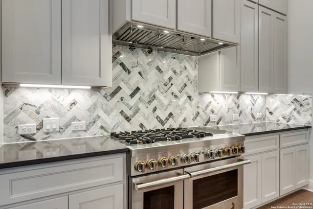 a kitchen with granite countertop a stove and a white cabinets