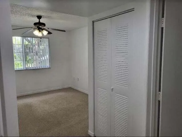 an empty room with windows and chandelier fan
