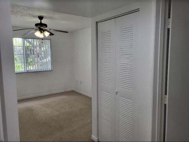 4159 Haverhill Road, Unit 1307 West Palm Beach, FL 33417 - Photo 7 of 14 an empty room with windows and chandelier fan