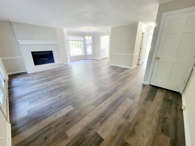 an empty room with wooden floor and fireplace