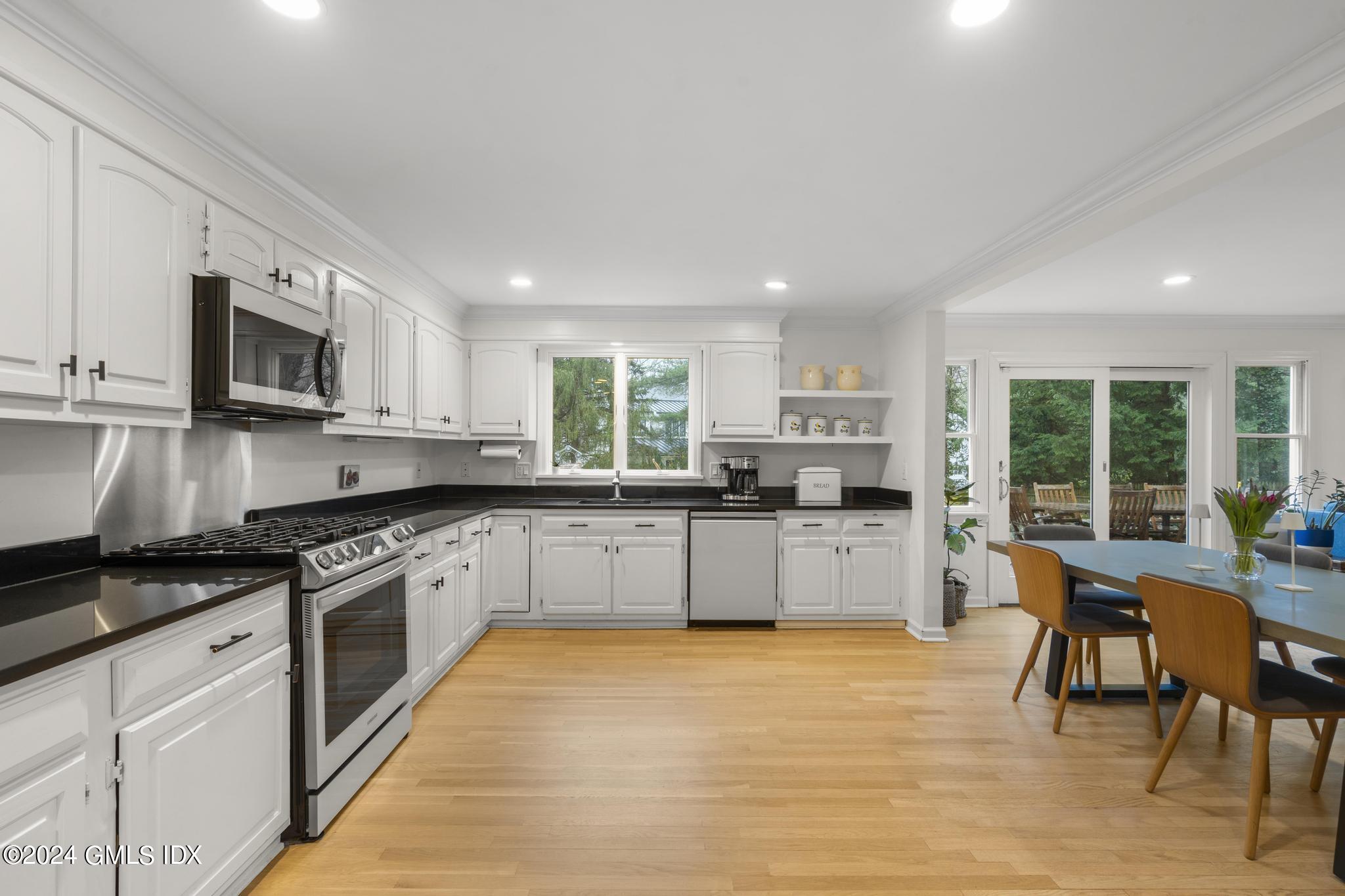 311 Cognewaugh Road Cos Cob, CT 06807 - Photo 6 of 28 a kitchen with stainless steel appliances granite countertop a stove top oven a sink dishwasher a dining table and chairs with wooden floor