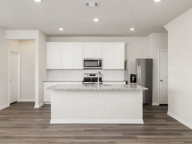 a large kitchen with stainless steel appliances granite countertop a stove a refrigerator and a microwave