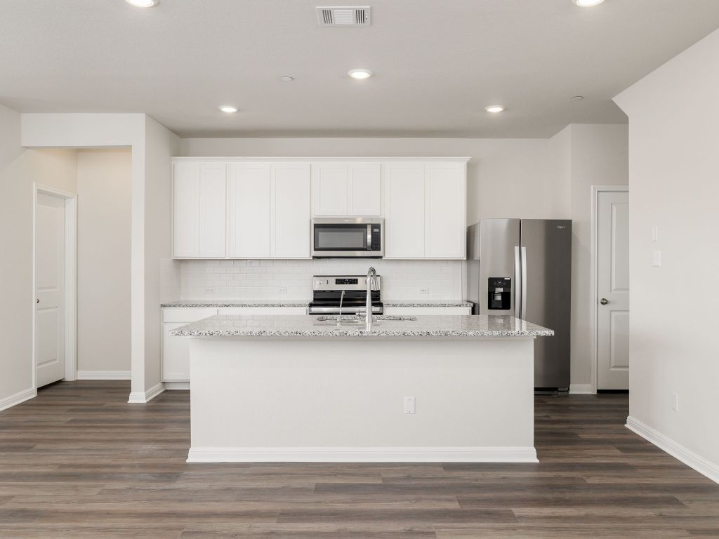 105 Texas Agate Drive, Unit 5 Kyle, TX 78640 - Photo 4 of 19 a large kitchen with stainless steel appliances granite countertop a stove a refrigerator and a microwave