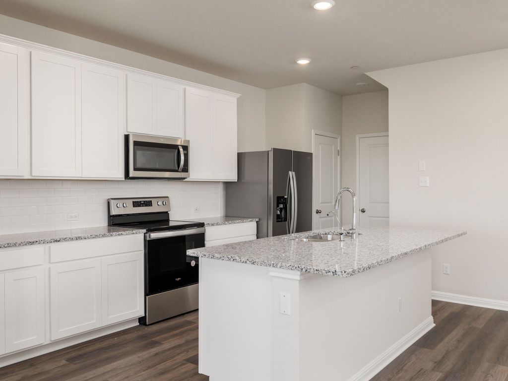 105 Texas Agate Drive, Unit 5 Kyle, TX 78640 - Photo 5 of 19 a kitchen with kitchen island a sink stainless steel appliances and cabinets