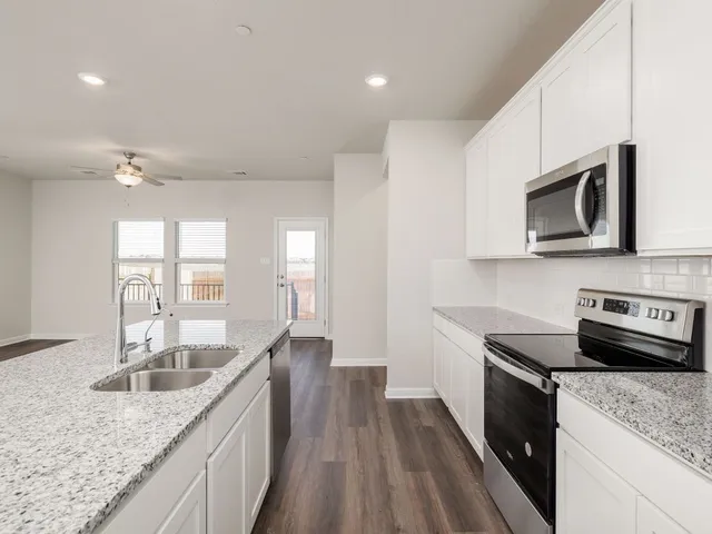 a kitchen with stainless steel appliances granite countertop a sink dishwasher stove and microwave with wooden floor