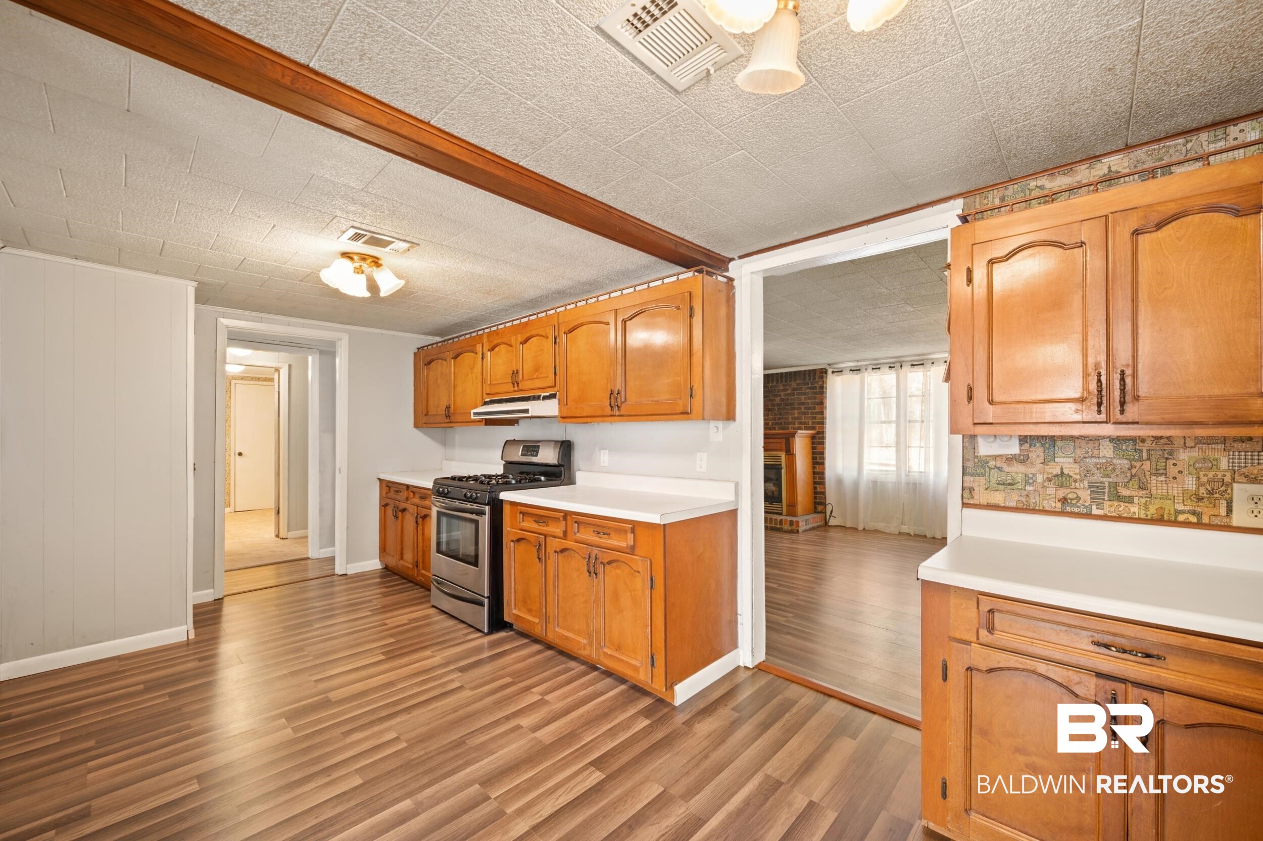 57623 Mary Hadley Road Perdido, AL 36562 - Photo 7 of 34 Kitchen with stainless steel gas stove, light countertops, light wood-type flooring, brown cabinetry, and under cabinet range hood