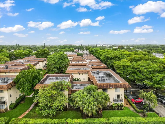 a view of a white house with a big yard plants and large trees