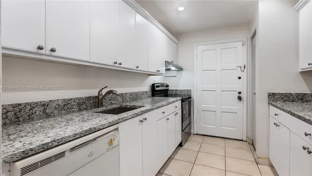 a kitchen with granite countertop a sink stainless steel appliances and white cabinets