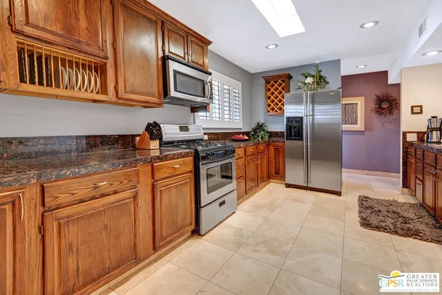 a kitchen with stainless steel appliances granite countertop a stove a sink dishwasher a refrigerator and cabinets with wooden floor