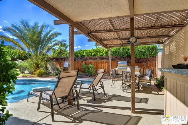 a view of a patio with table and chairs potted plants and a palm tree