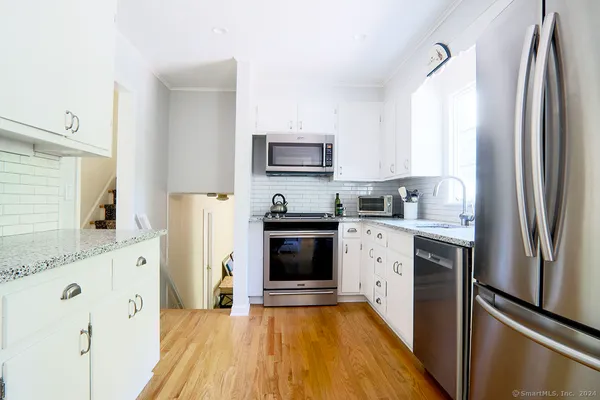 a kitchen with granite countertop a refrigerator stove and sink