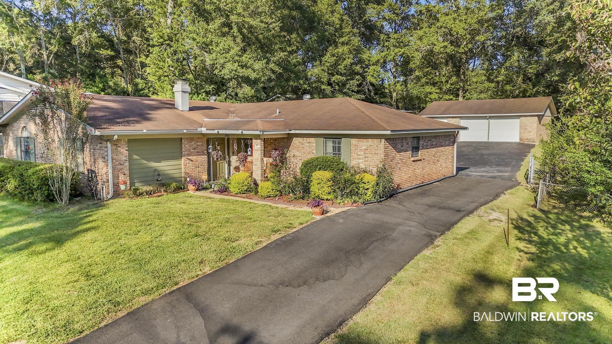 2573 E Road Mobile, AL 36693 - Photo 1 of 45 Single story home featuring a detached garage, an outdoor structure, brick siding, a front lawn, and a chimney